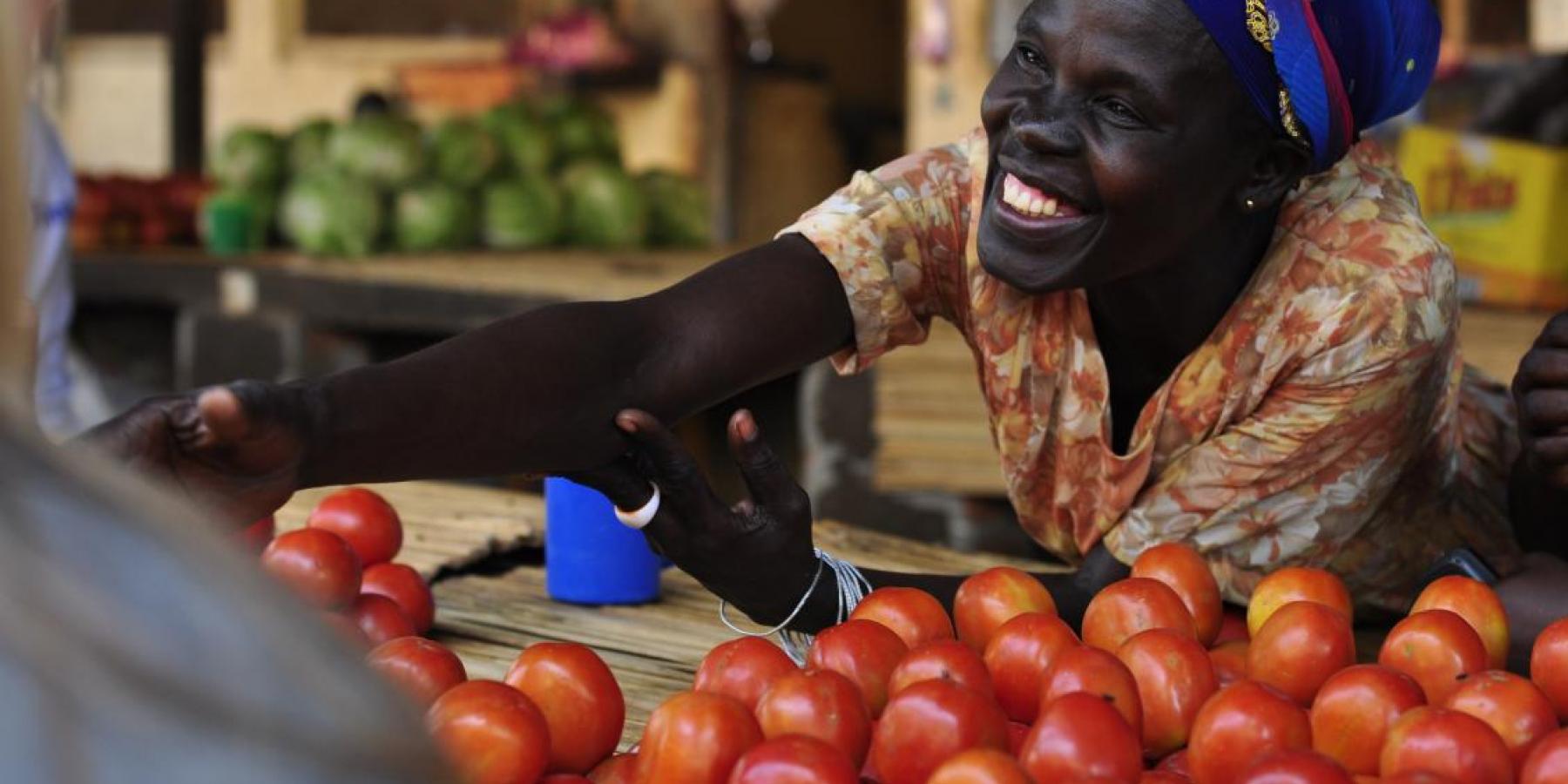A member of a women's microfinance group sells produce at a market in Gulu, Uganda. 