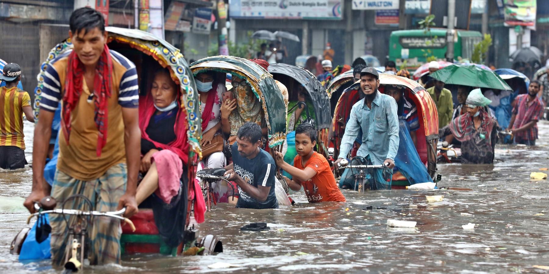 Vehicles try to drive through a flooded street in Dhaka, Bangladesh
