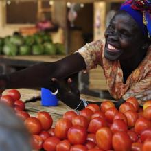 A member of a women's microfinance group sells produce at a market in Gulu, Uganda. 