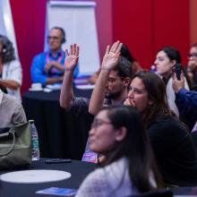 people at an event raising hand smiling 