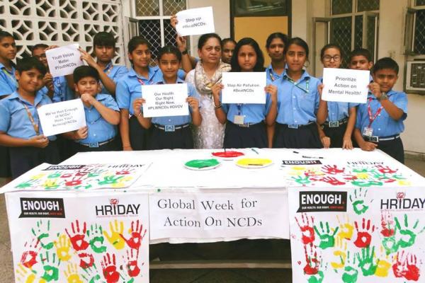 Members of HRIDAY in India, hold up small signs with slogans supporting the Week for Action.